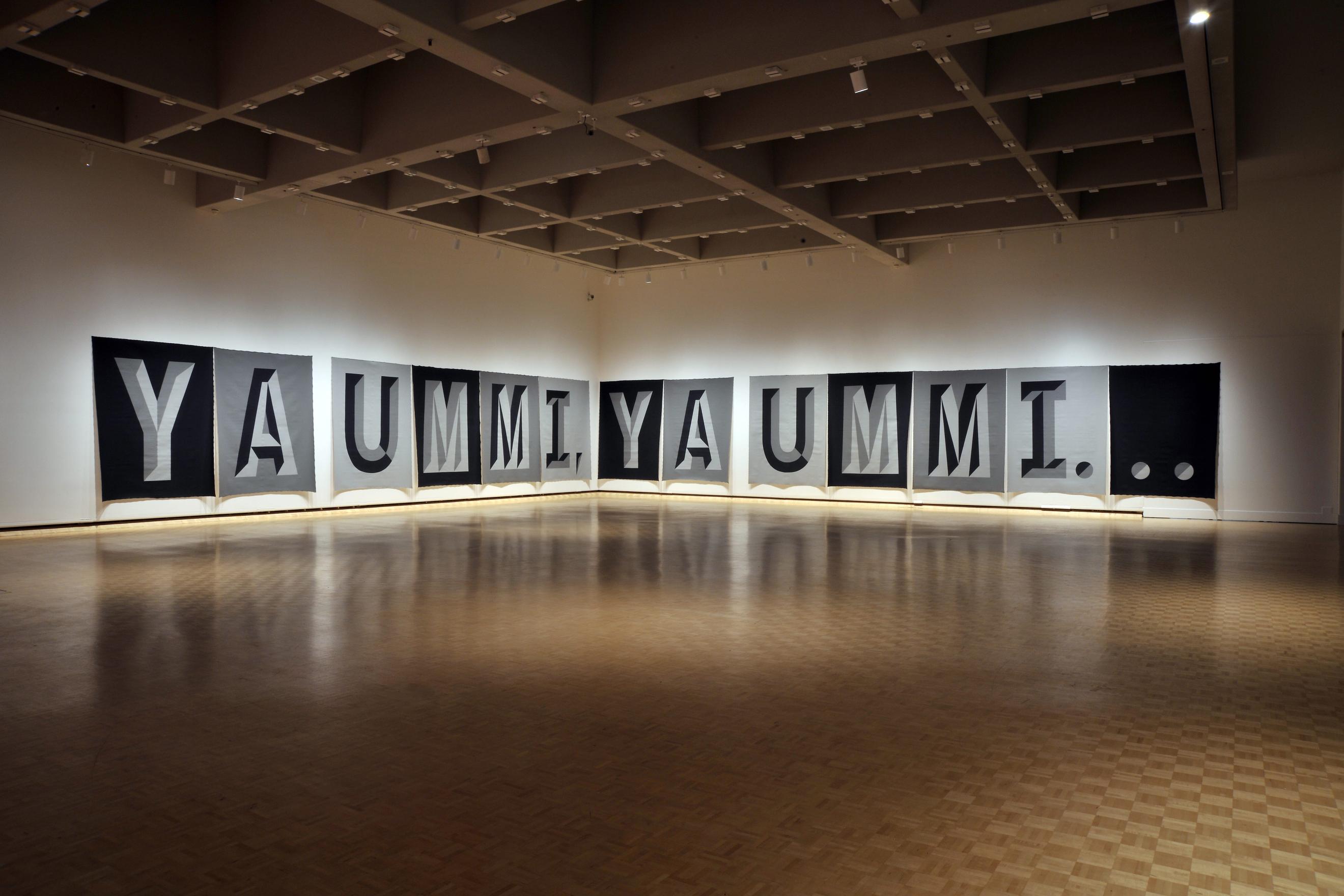 13 large screen prints hang along the walls in a corner of a large empty gallery space. Each one has one letter on it done in greyscale Superstar Shadow font. Together they spell out: YA UMMI, YA UMMI… The scale of the words cuts through the empty space, lingering as if they were midway through being uttered at that moment. 