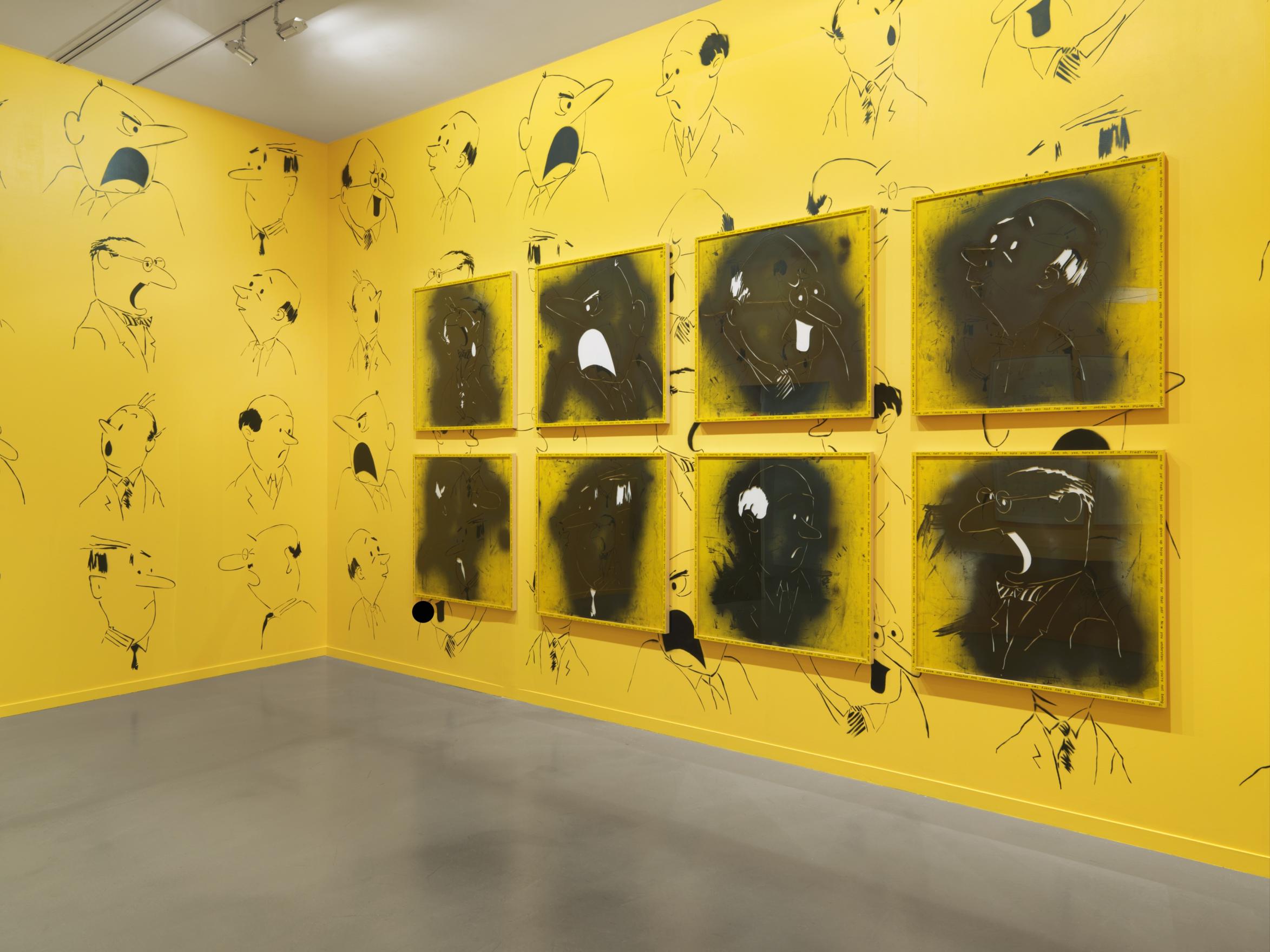 Bright yellow gallery walls are lined floor to ceiling with black spray painted stencils of shouting men’s heads. Six framed stencils blackened with paint are framed on the right wall.