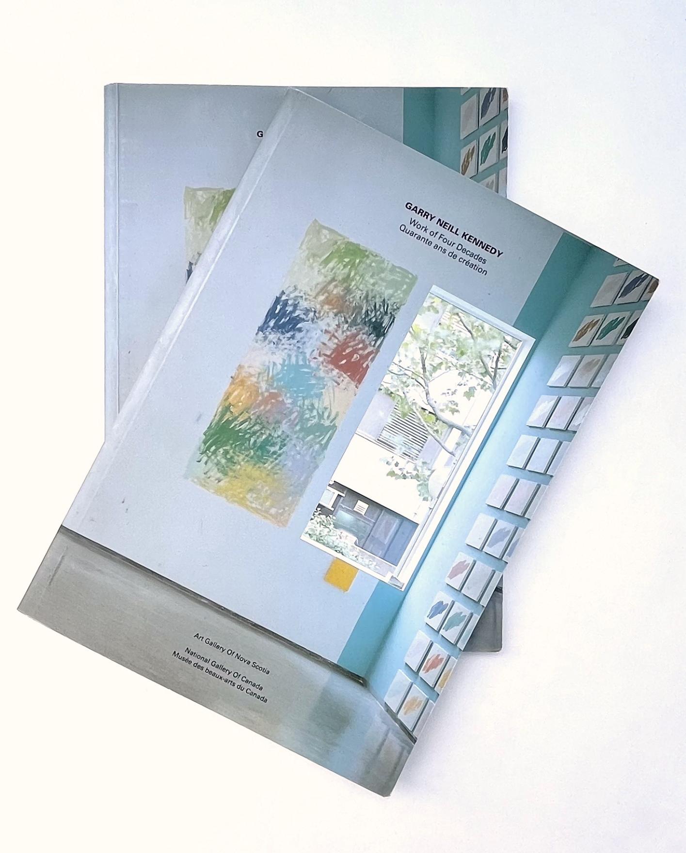 Two exhibition catalogues titled Garry Neill Kennedy: Work of Four Decades are stacked off center, their covers show a window and an expressive wall-painting with the same dimensions, made of layers of overlapping scribbles in rust oranges, deep ocean blues and evergreens.