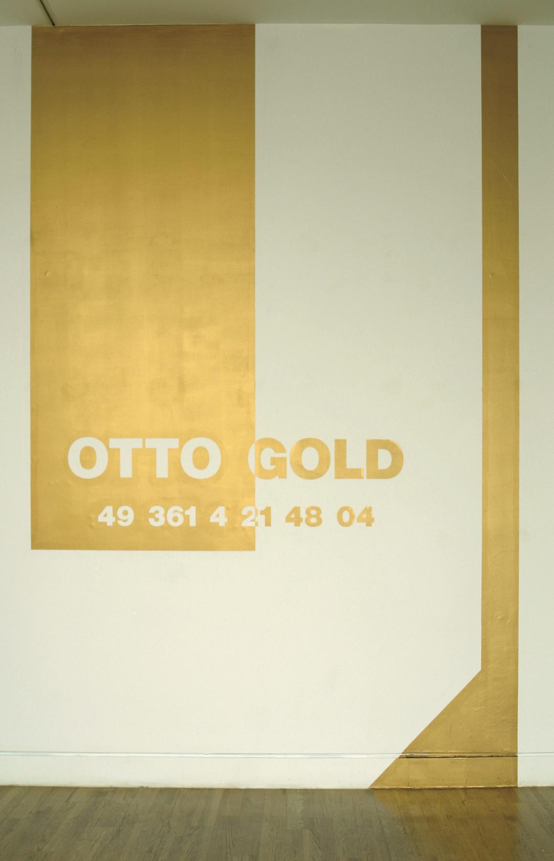 A large U is painted on the gallery wall from floor to ceiling in metallic gold paint. Half way down the U the words OTTO GOLD are written in contrasting tones, the numbers 49 361 4 21 48 04 are written below. This is the international phone number for Mr. Otto Gold of Germany. 